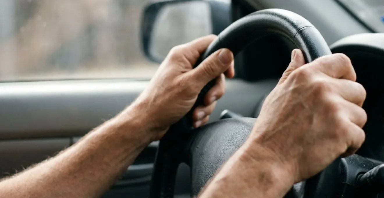 Gros plan sur les mains d'un conducteur tenant un volant, symbolisant la protection personnelle et la sécurité au volant