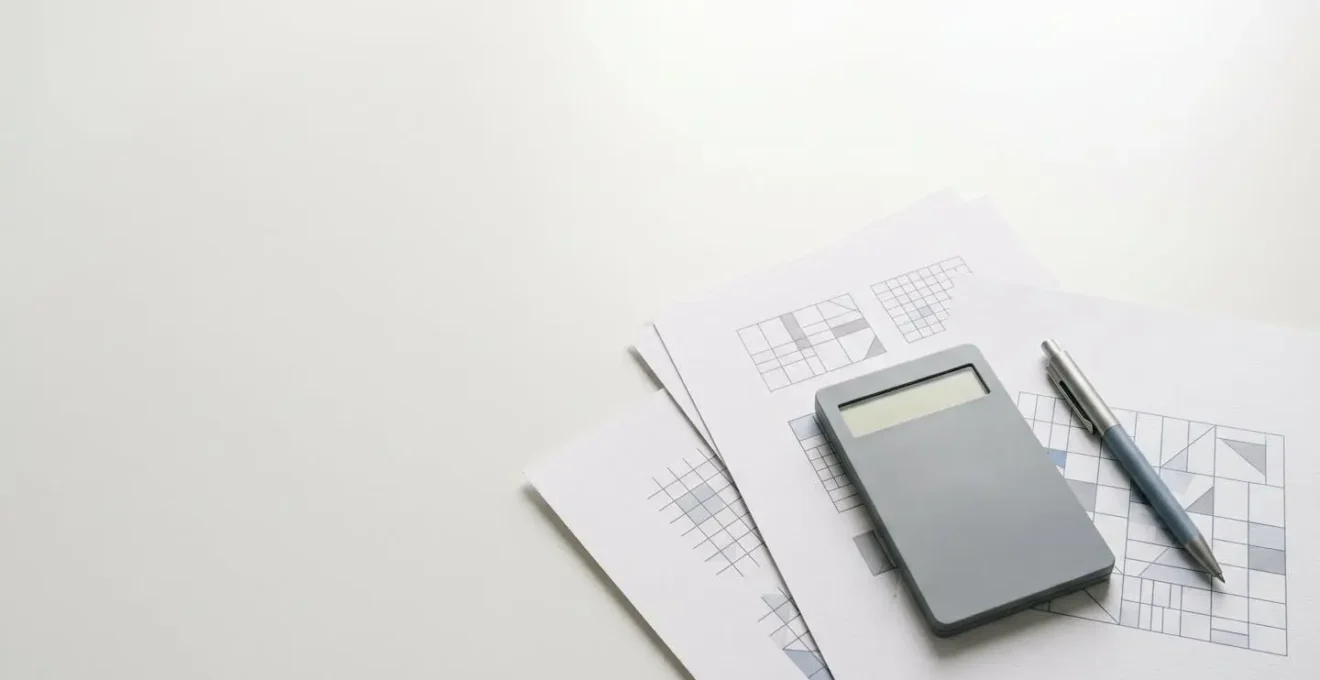 Vue en plongée d'une table avec calculatrice, stylo et feuilles de papier montrant des chiffres abstraits, dans une ambiance de prise de décision financière